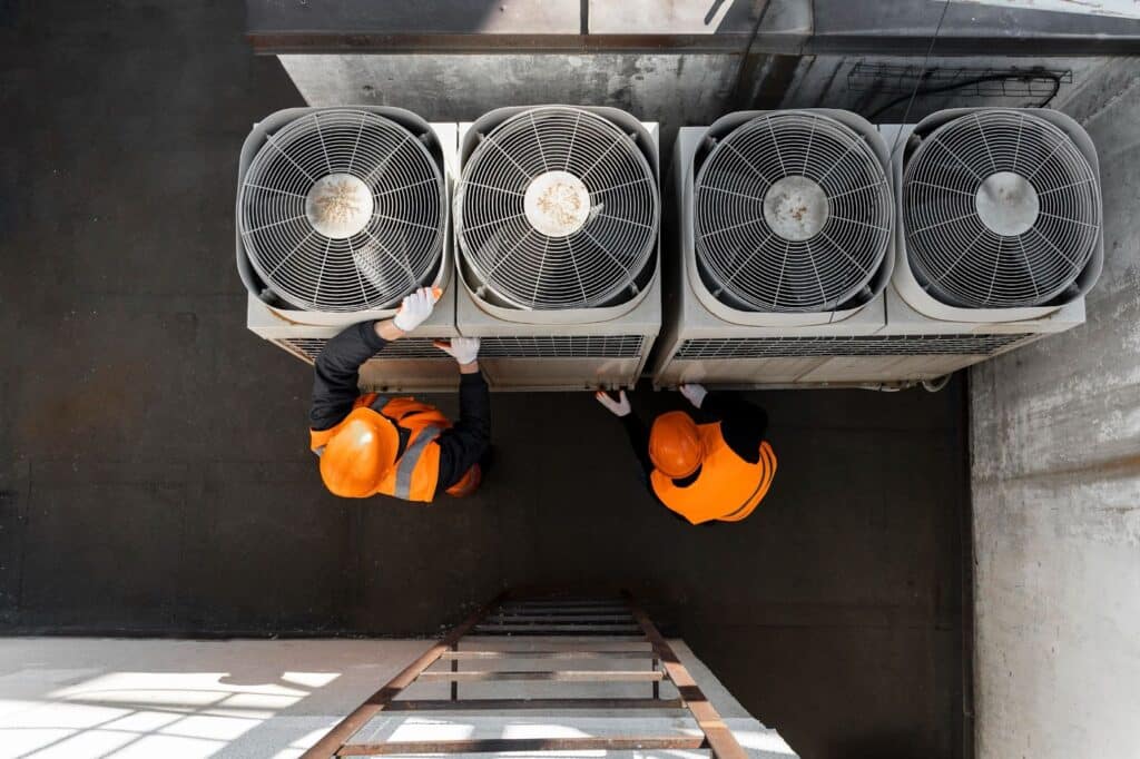 Two workers adjusting energy-efficient HVAC system operation
