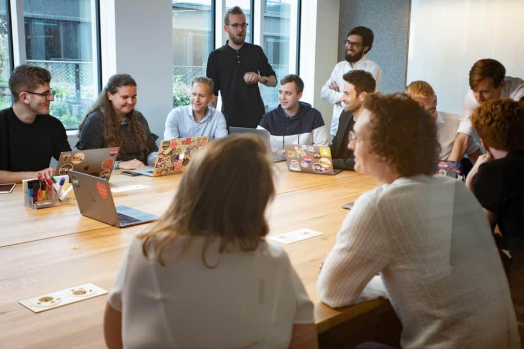 Group of professional men and women sitting and standing around a conference table strategizing together